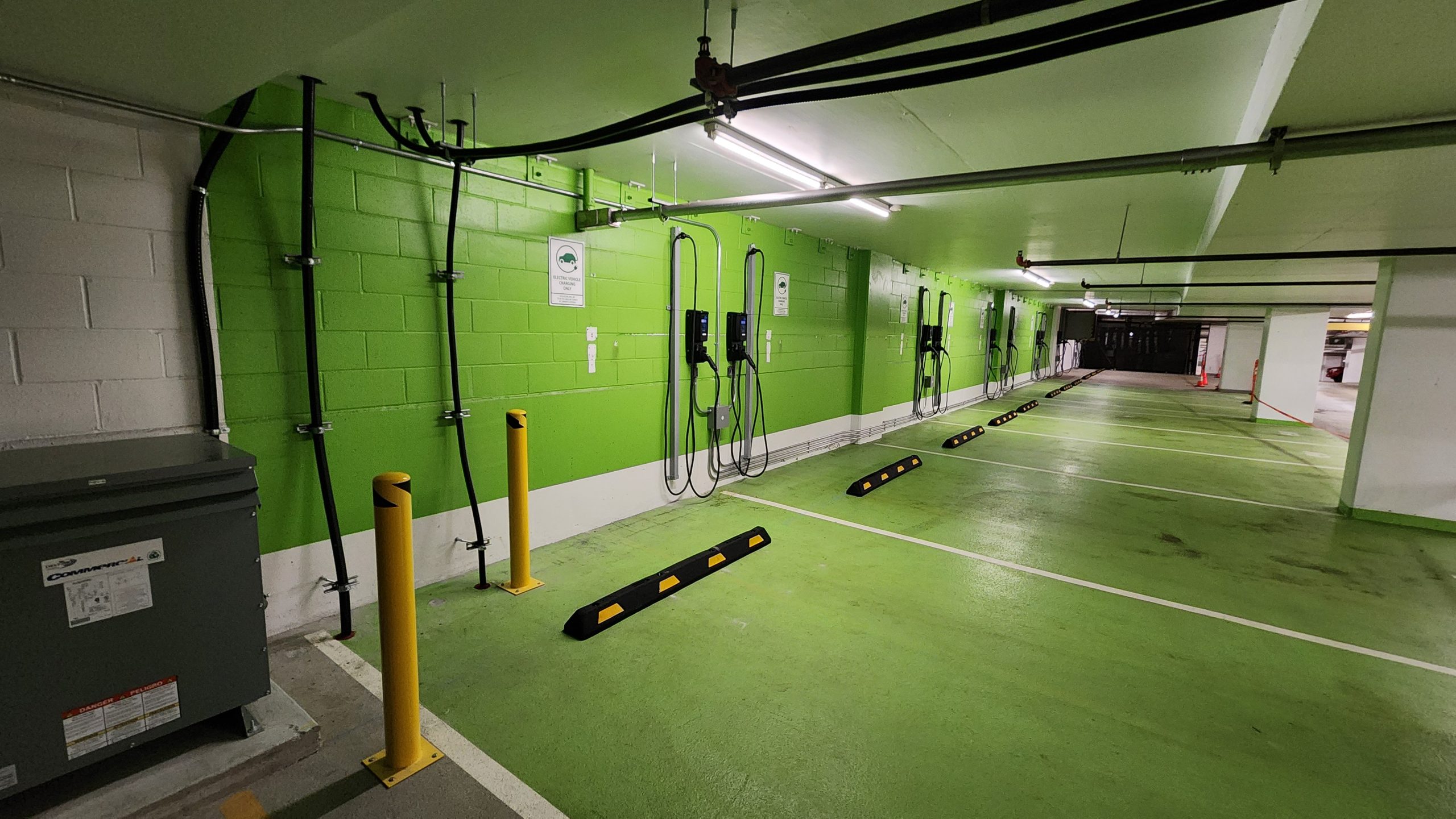 A commercial parking lot painted green, equipped with EV charging facilities.
